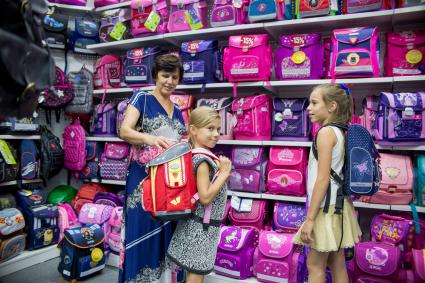 Челябинск. Женщина помогает выбрать рюкзак в отделе школьных товаров.