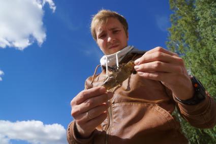 Свердловская область. Экологическая катастрофа.  Корреспондент \'Комсомольская правда- Екатеринбург Андрей Леонов\' держит вынесеную на берег рыбу. Мор рыбы в воде из-за цветения сине-зеленых водорослей в Черноисточинском пруду, водой которого снабжается город Нижний Тагил