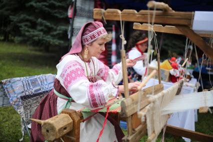 Челябинская область.  Женщина в национальном костюме ткет на ткацком станке на XXIV Всероссийском Бажовском фестивале народного творчества.