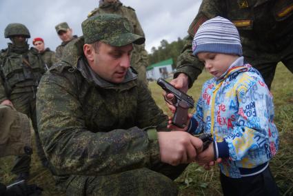 Екатеринбург. Военнослужащий дает подержать настоящие пистолеты Макарова маленькому мальчику. Выставка вооружения в рамках международной военно-технической выставке \'Армия-2016\'