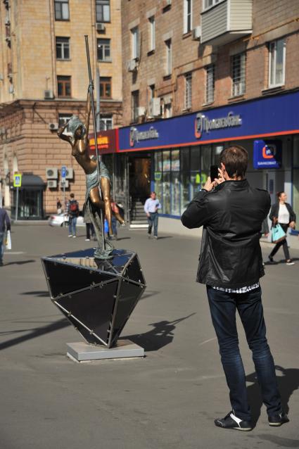 Москва.   Мужчина фотографирует памятник стриптизерше на улице Проспект Мира.