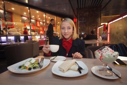 Москва. Девушка за столиком  в первой кофейне при московском  метро `М Кафе` на станции   `Выставочная` .