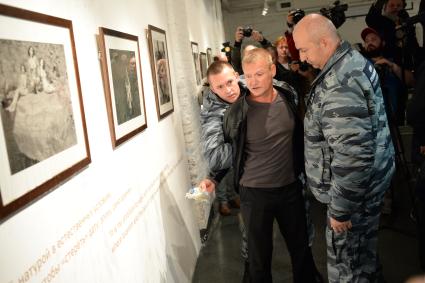 Москва.  Мужчина заливает жидкостью фотографию на скандальной фотовыставке  Джока Стерджеса `Без смущения` в центре фотографии  имени  братьев Люмьер.