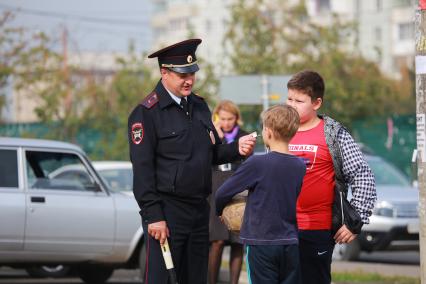 Красноярск. Сотрудник  ГИБДД разговаривает с детьми на одной из улиц города.