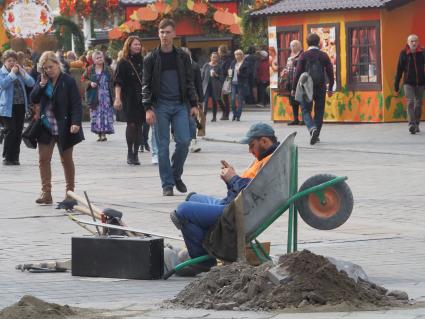 Москва. Рабочий отдыхает на улице, где проходит фестиваль `Золотая осень`.