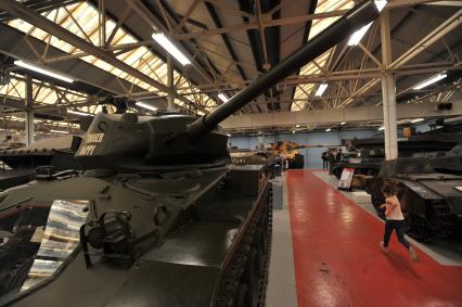 Англия. Лондон.  Девочка бегает в одном из залов  музея танков в Бовингтоне.