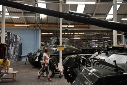 Англия. Лондон.  Посетители с ребенком  в одном из залов  музея танков в Бовингтоне.