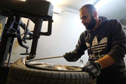 Екатеринбург. Сотрудник шиномонтажной мастерской, разбортовует автомобильное колесо, для замены на зимнюю резину
