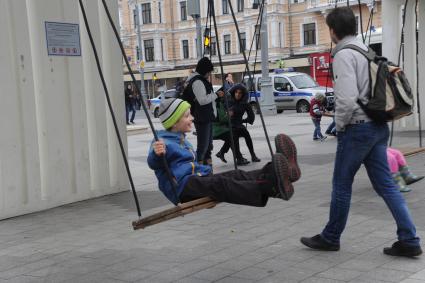 Москва. Мальчик качается  на качелях на Триумфальной площади.