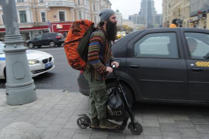 Москва.  Мужчина едет на самокате по Тверской улице.