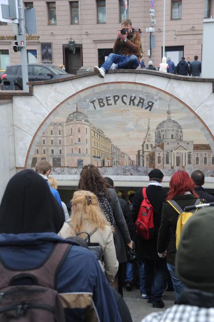 Москва. Молодой человек   фотографирует прохожих у входа  в метро `Тверская`.