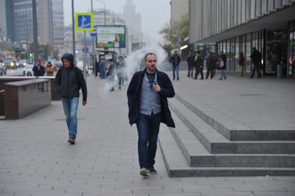 Москва. Мужчина курит электронную сигарету  на Новом Арбате.