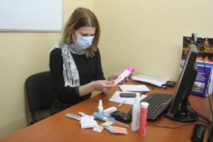 Иркутск. Девушка на рабочем месте в офисе лечится от простуды.