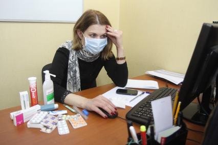 Иркутск. Девушка на рабочем месте в офисе  лечится от простуды.