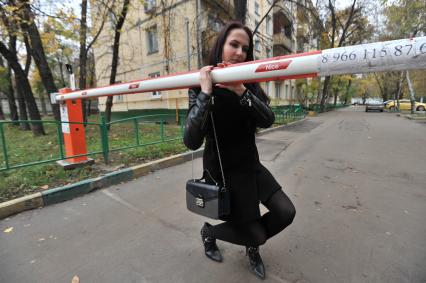 Москва. Девушка пытается поднять шлагбаум во дворе жилого дома.
