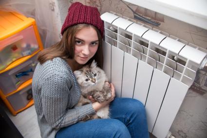 Челябинск.  Девушка с кошкой  сидит возле батареи центрального отопления.
