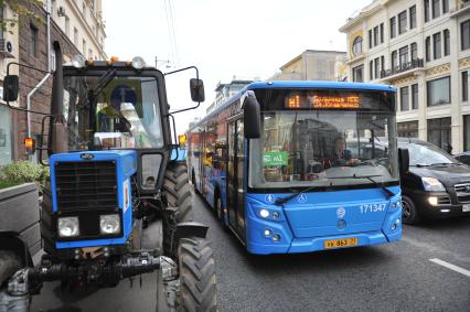 Москва.  Трактор и автобус  маршрута М1 на Тверской улице.