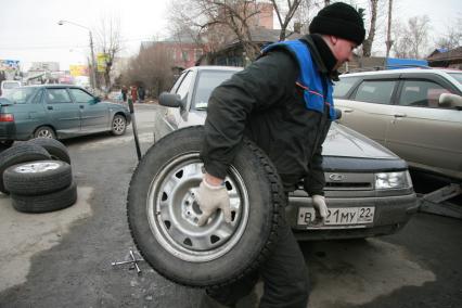 Барнаул. Работник шиномонтажной мастерской меняет колеса у автомобиля.