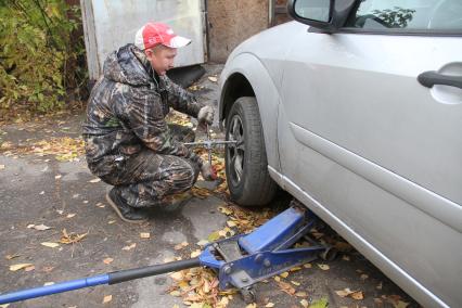 Нижний Новгород.  Работник шиномонтажной мастерской меняет колеса у автомобиля.