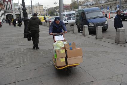 Москва.  Грузчик везет тележку с коробками  рядом с Казанским вокзалом.