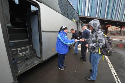 Москва. Кондуктор проверяет билет у пассажира перед отправлением автобуса у здания международного автовокзала `Южные ворота` в Люблино.