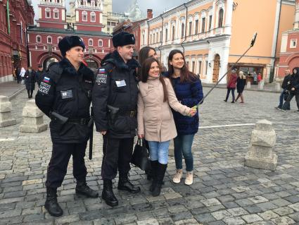 Москва.  Девушки делают селфи с сотрудниками туристической полиции на Красной площади.