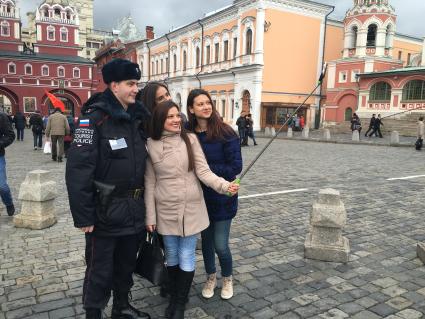 Москва.  Девушки делают селфи с сотрудником туристической полиции на Красной площади.