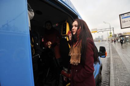 Москва. Девушка при входе в автобус прикладывает проездной билет к валидатору.