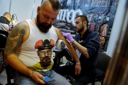 Екатеринбург. Уральский фестиваль искусства татуировки \'Ural tattoo convention 2016\', Тату-мастер набивает мужчине татуировку на плече