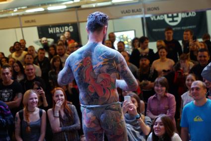 Екатеринбург. Уральский фестиваль искусства татуировки \'Ural tattoo convention 2016\'. Посетители фестиваля фотографирют татуировки конкурсанта покрывающие все его тело