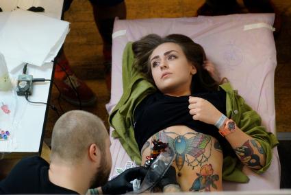 Екатеринбург. Уральский фестиваль искусства татуировки \'Ural tattoo convention 2016\'. Тату-мастер набивает татуировку посетительнице фестиваля