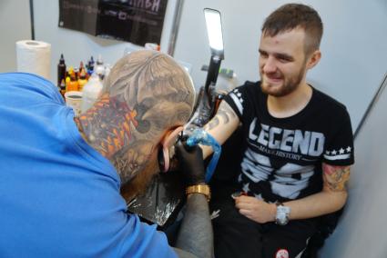 Екатеринбург. Уральский фестиваль искусства татуировки \'Ural tattoo convention 2016\'. Тату-мастер набивает татуировку посетительнице фестиваля