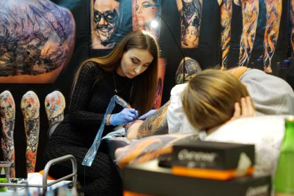 Екатеринбург. Уральский фестиваль искусства татуировки \'Ural tattoo convention 2016\'. Тату-мастер набивает татуировку посетителю фестиваля