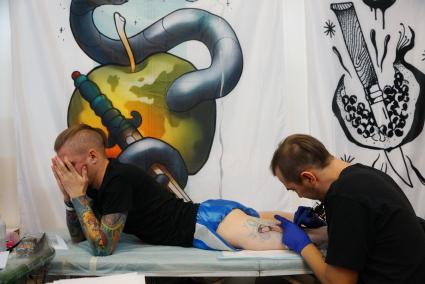 Екатеринбург. Уральский фестиваль искусства татуировки \'Ural tattoo convention 2016\'. Тату-мастер набивает татуировку посетителю фестиваля