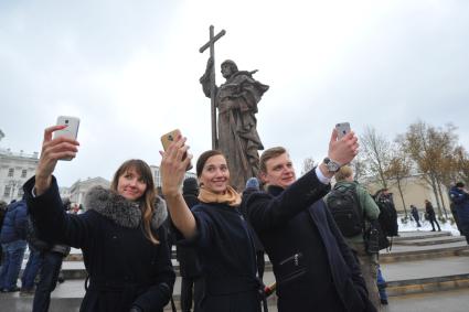 Москва.  Молодые люди делают селфи на фоне памятника святому равноапостольному князю Владимиру, установленному на Боровицкой площади.