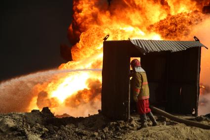 Ирак, Кайара. Пожарные заливают водой горящие нефтяные скважины, подожженные отступающими к Мосулу боевиками `Исламского Государства` (запрещенная в России экстремистская организация).