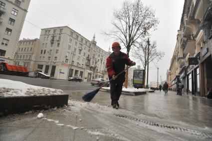 Москва.  Сотрудник коммунальных служб убирает снег  на  Тверской улице.