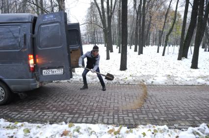 Москва. Дворник посыпает дорожки песком.