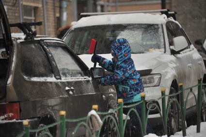 Москва. Мальчик очищает машину от снега.