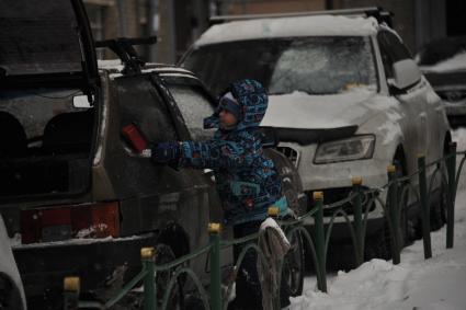 Москва. Мальчик очищает машину от снега.