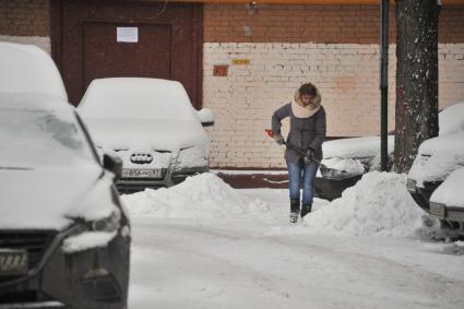 Москва.  Женщина убирает снег во дворе.