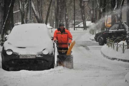 Москва.  Дворник со снегоуборочной машиной  во дворе.