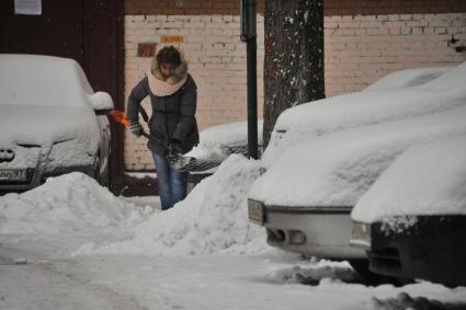 Москва.  Женщина убирает снег во дворе.