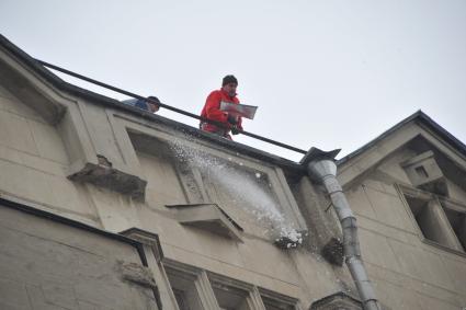 Москва. Дворник сбрасывает снег с крыши.