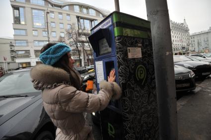 Москва. Девушка оплачивает парковку автомобиля через паркомат.