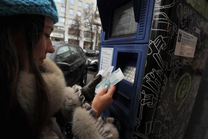 Москва. Девушка оплачивает парковку автомобиля через паркомат.