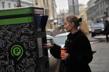 Москва. Девушка оплачивает парковку автомобиля через паркомат.