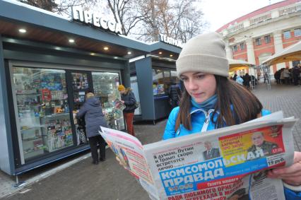 Москва.  Девушка  с газетой  `Комсомольская правда` у обновленного  киоска `Пресса` у метро Краснопресненская.