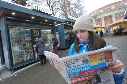 Москва.  Девушка  с газетой  `Комсомольская правда` у обновленного  киоска `Пресса` у метро Краснопресненская.