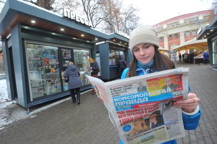 Москва.  Девушка  с газетой  `Комсомольская правда` у обновленного  киоска `Пресса` у метро Краснопресненская.